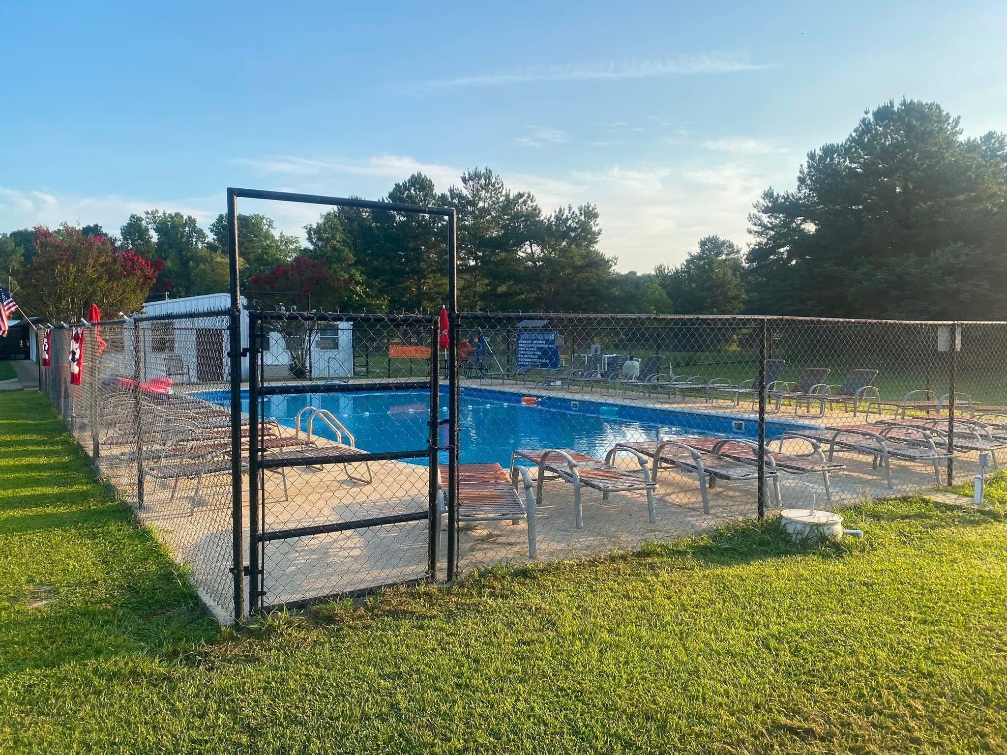 The campground swimming pool inside its fence, with loungers set out along the deck.