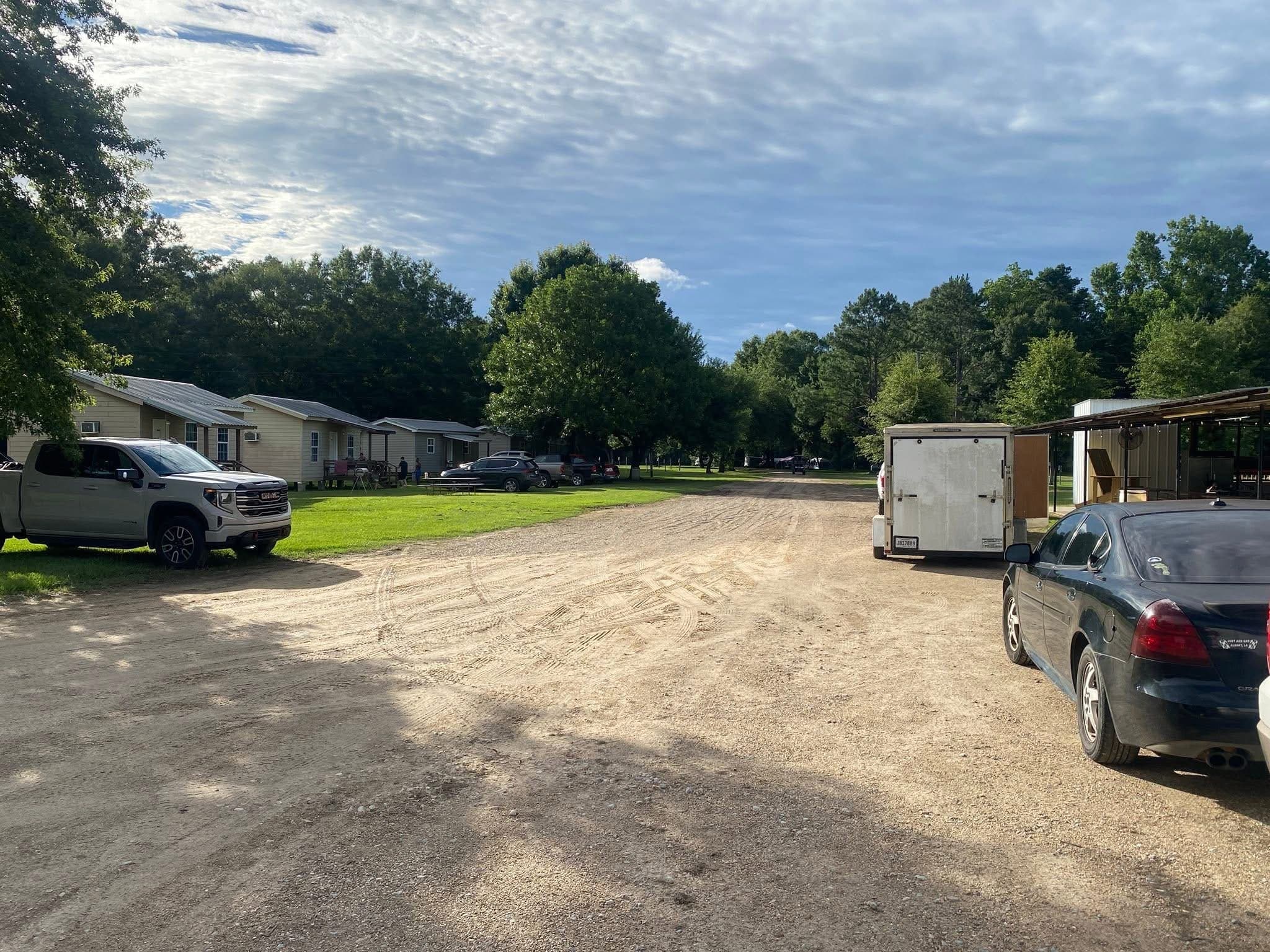 A wide gravel road between camping sites, with cabins and trailers along one side.